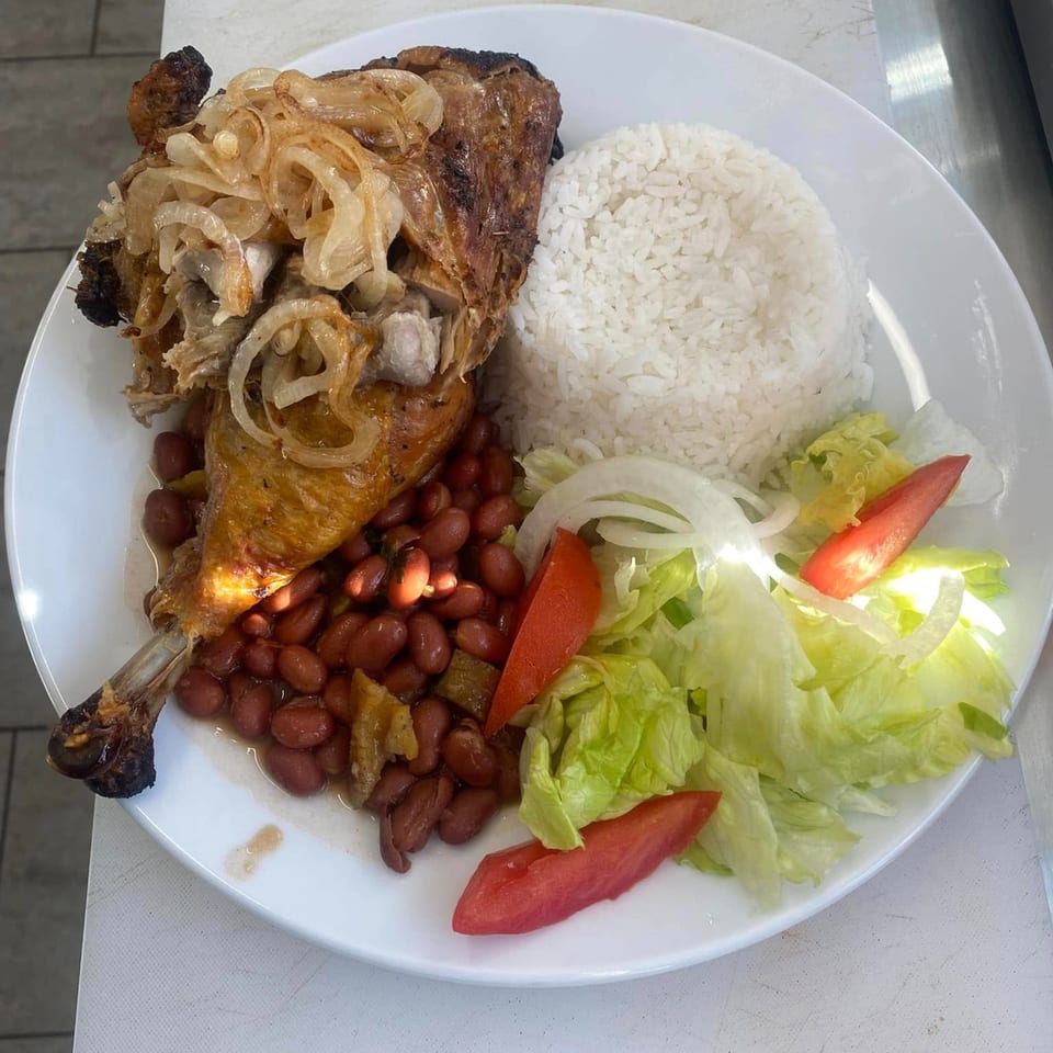 Roasted chicken leg with caramelized onions, red beans, white rice, and a side salad.